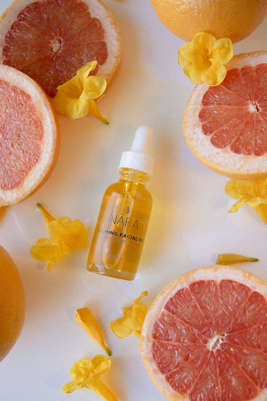 Calming Face Oil Bottle and Grapefruit Slices and Flowers